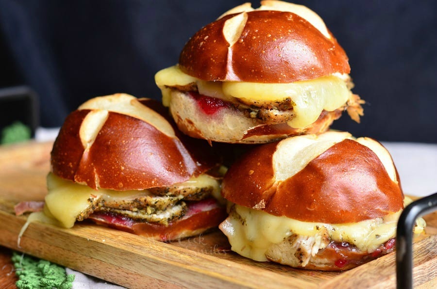 4 cranberry asiago turkey sliders stacked on a wooden cutting board viewed close up