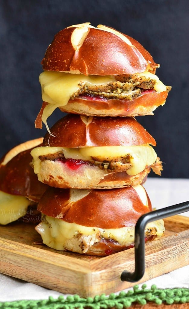 4 cranberry asiago turkey sliders stacked as a tower on a wooden cutting board