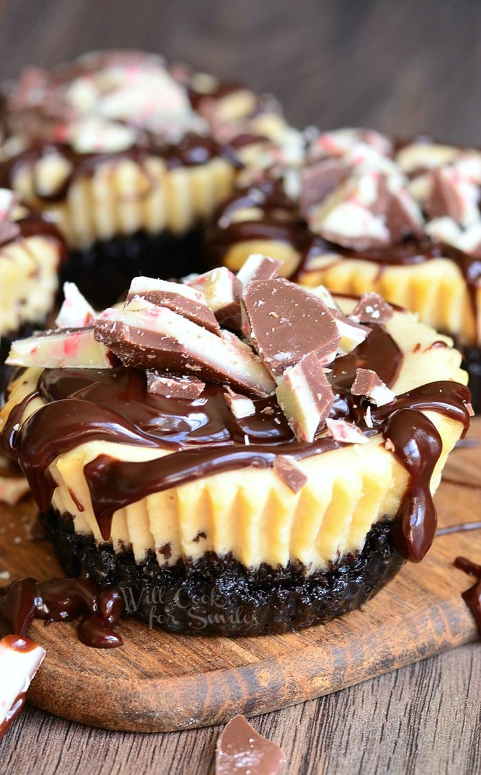 4 peppermint mocha mini cheesecakes sitting on a small paddle cutting board on a dark wood table