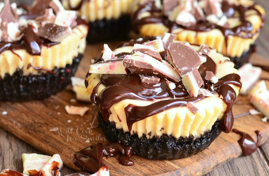 vertical photo of Peppermint Mocha Mini Cheesecakes with peppermint candy on top on a cutting board 