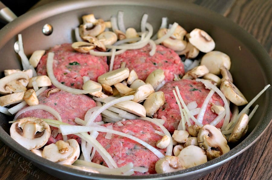 uncooked Salisbury Steak with mushrooms and onions in a pan 