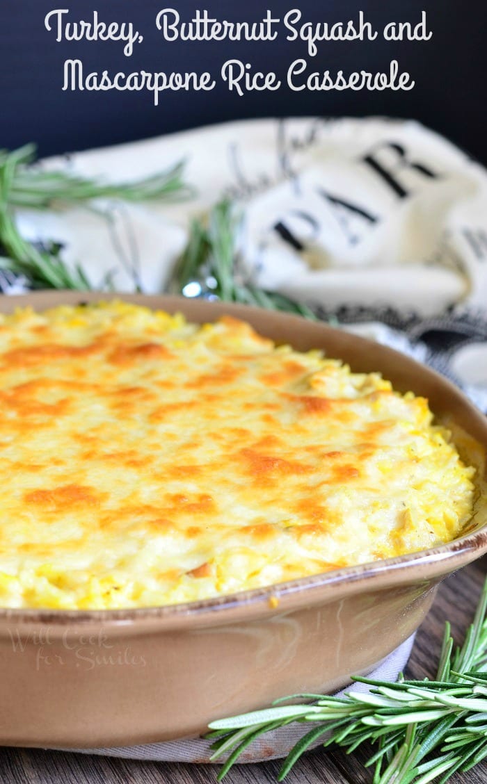 Large round baking dish filled with turkey butternut squash and mascarpone rice casserole on a wood table with a white towel in the background
