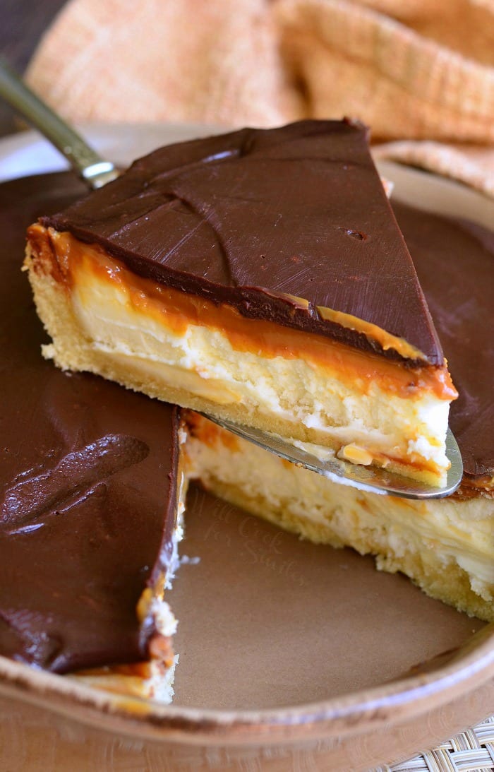 Twix Cheesecake Pie being lifted out of pie pan with a pie spatula 