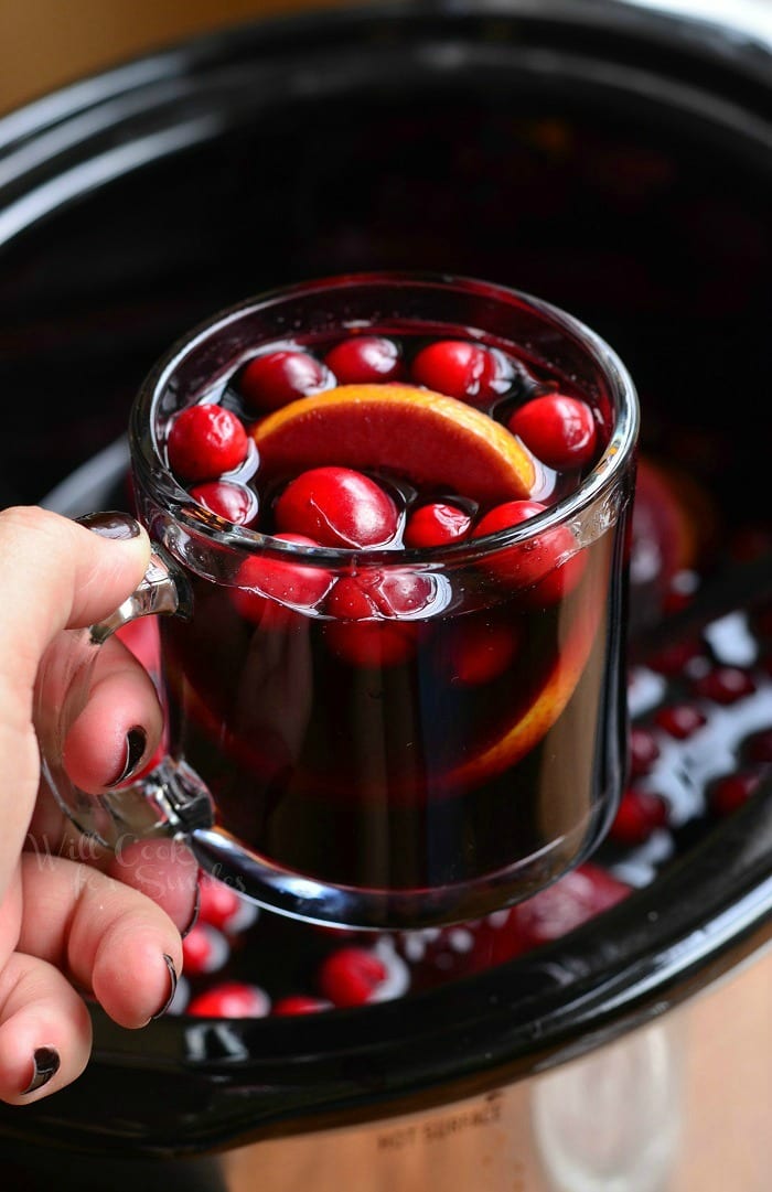 holding Orange Cranberry Sangria in a glass mug with orange and cranberries inside 