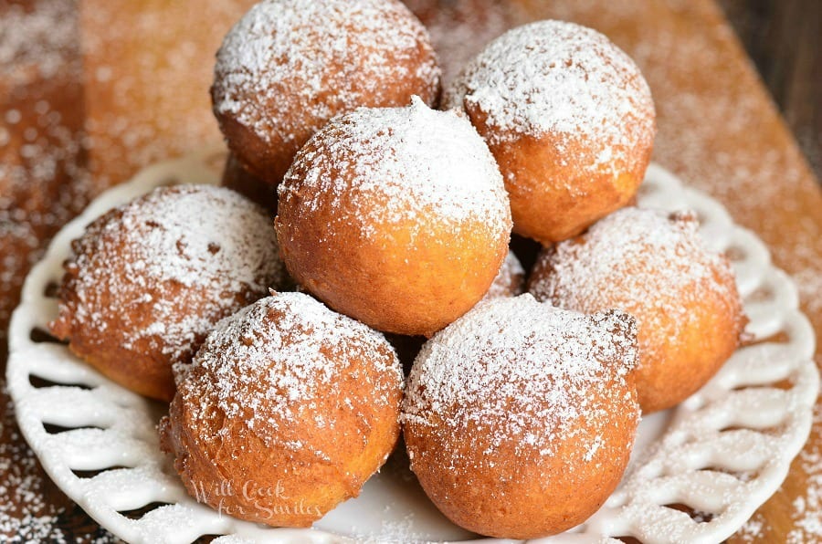 Ricotta Doughnut holes with powdered sugar on top stacked on a white plate 