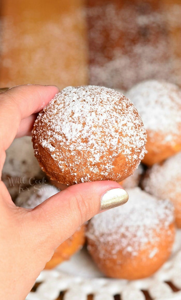 holding donut hole with powdered sugar on top 