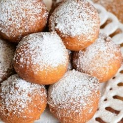 Easy Ricotta Doughnuts piled on a decorative round white plate with powdered sugar topping the doughnuts as viewed from above