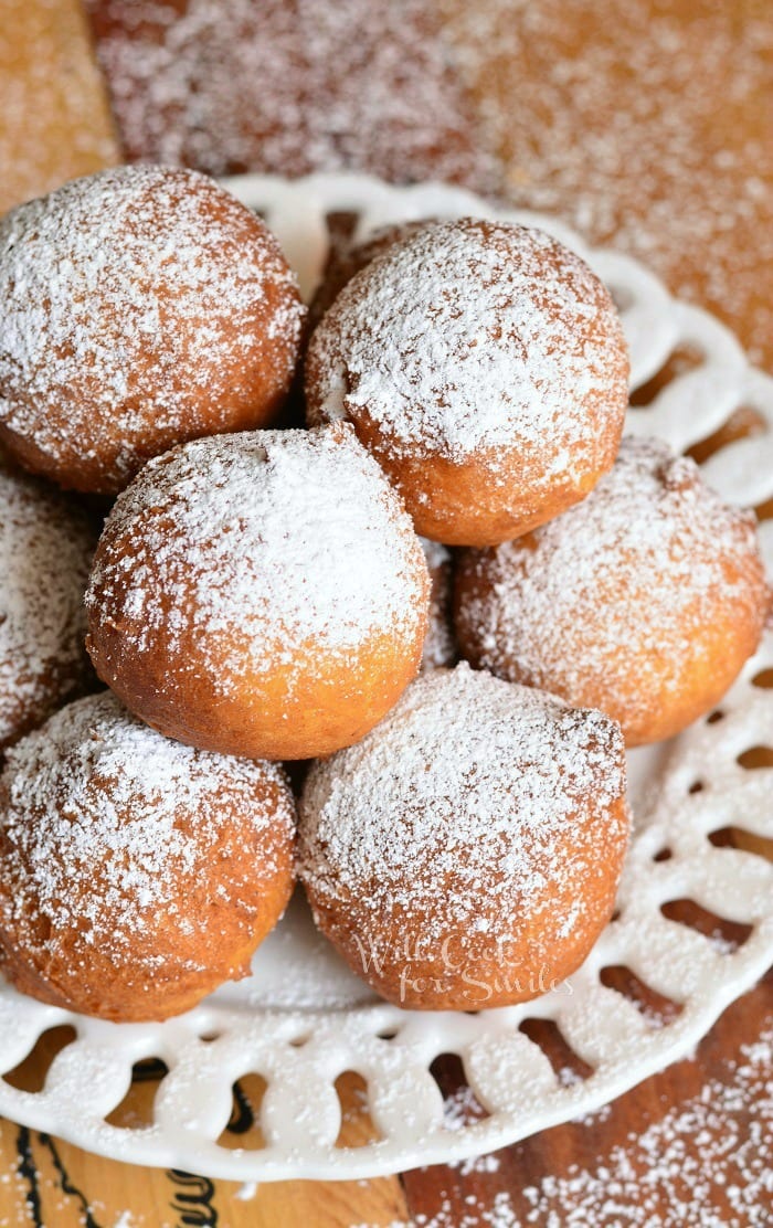 Easy Ricotta Doughnuts piled on a decorative round white plate with powdered sugar topping the doughnuts as viewed from above