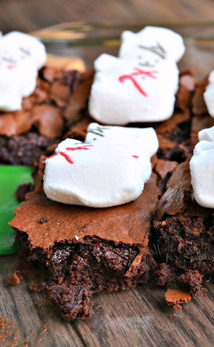 Brownies with snowman marshmallows on top in a clear glass baking pan 