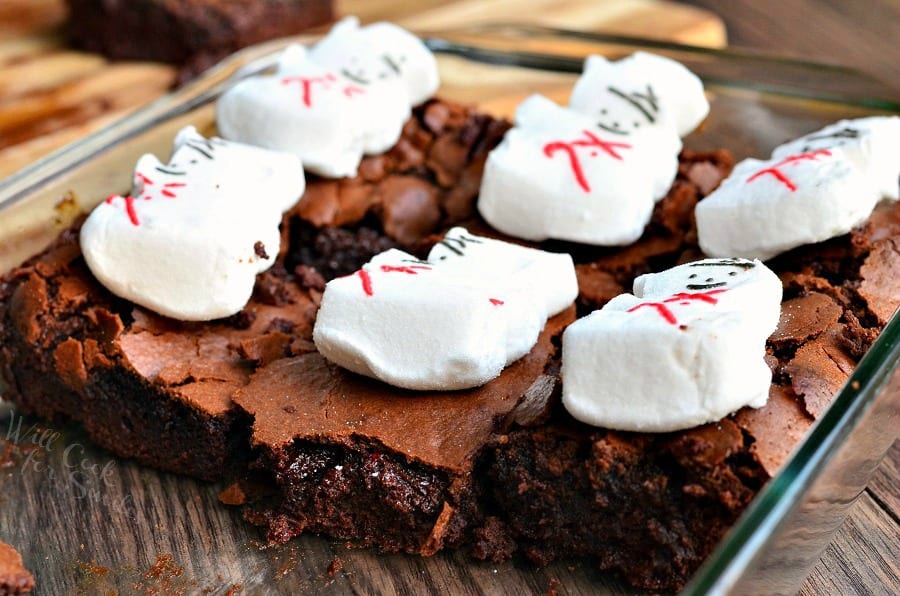 Brownies with snowman marshmallows on top in a clear glass baking pan 