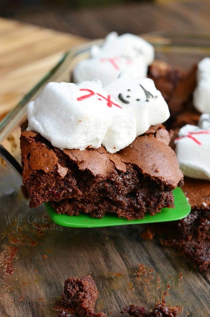 Brownies with snowman marshmallows on top on a green spatula 