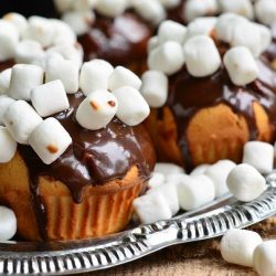 close up view of a silver platter with hot chocolate doughnut muffins topped with mini marshmallows