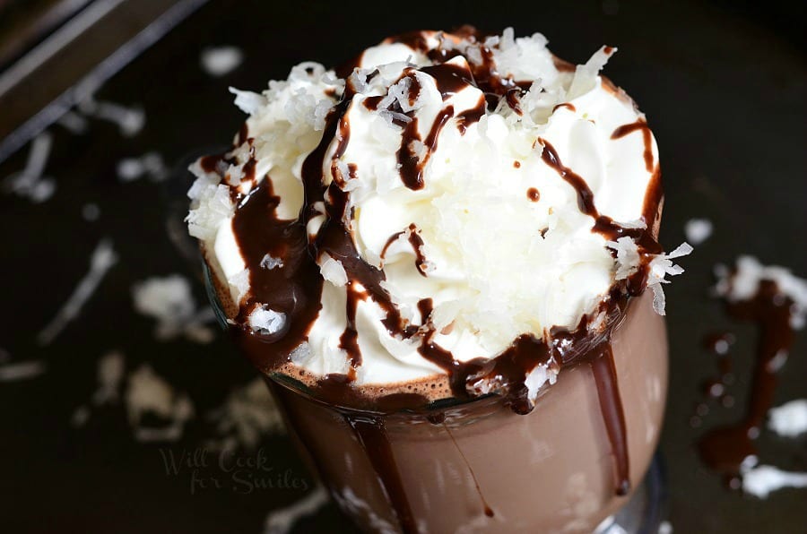 top view photo of Hot Chocolate in a clear glass with whipped cream, chocolate sauce, and shredded coconut on top  