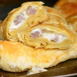 Sausage and gravy pastries piled on a baking try on a wooden table