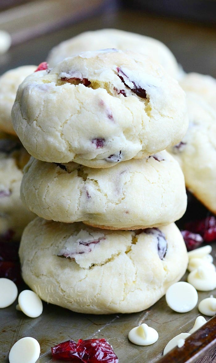 White Chocolate cookies with Cranberries staked on a cutting board with white chocolate chips 