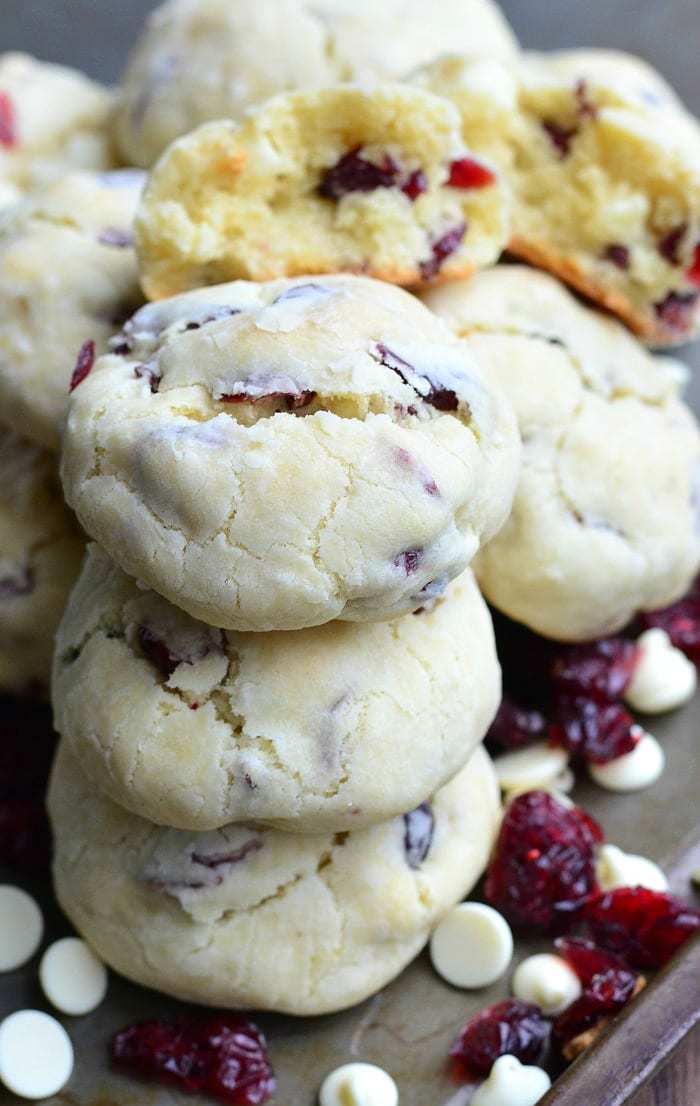 White Chocolate cookies with Cranberries staked on a cutting board with white chocolate chips 