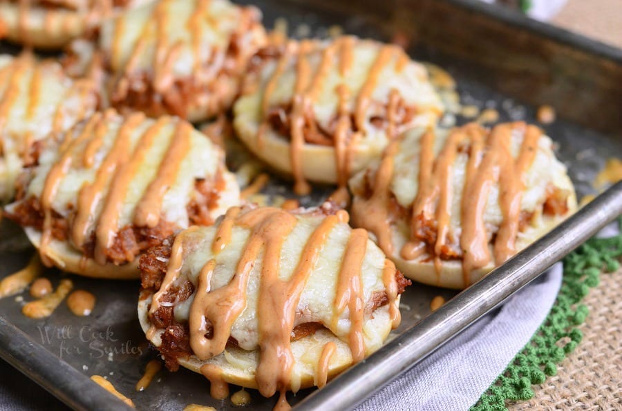 Bagel with BBQ smoked chicken, Monterrey Jack and Asiago cheeses, and topped with BBQ Ranch dressing on a baking dish 