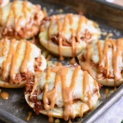 Metal baking sheet tray with asiago BBQ chicken bagel bites with sauce drizzled across the top