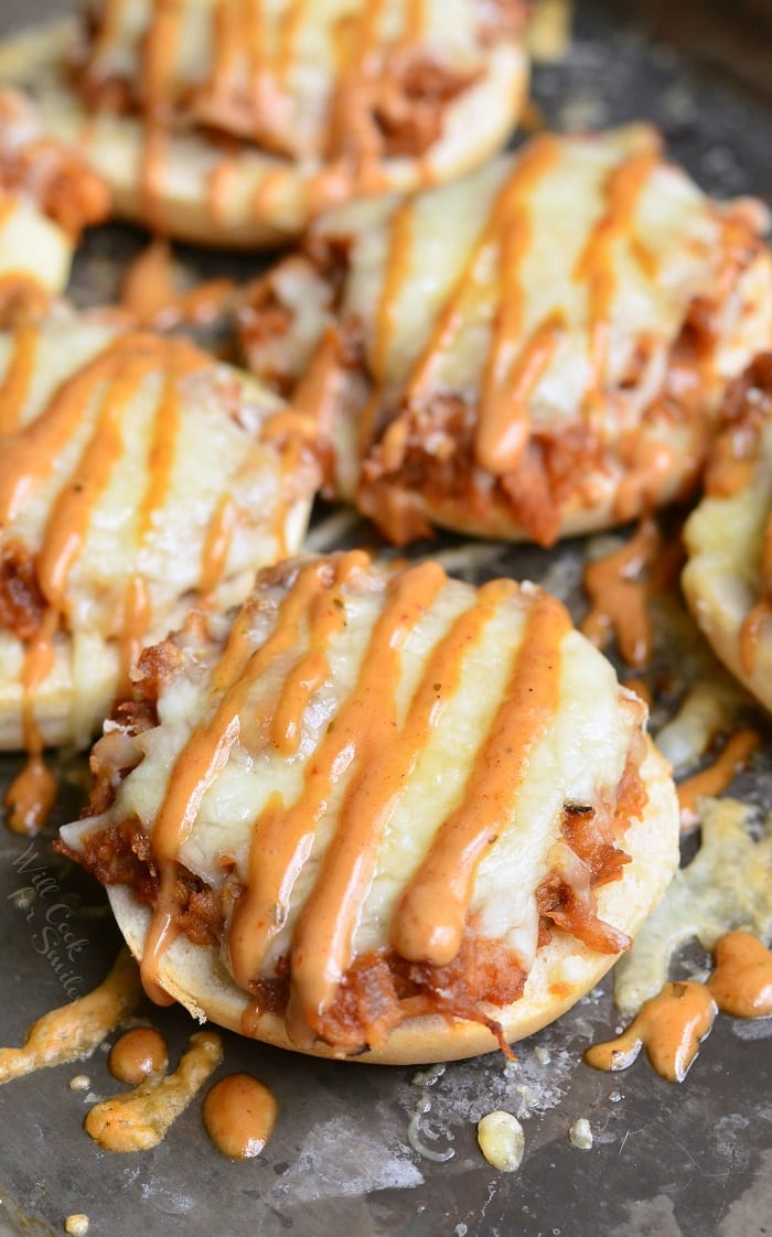 Bagel with BBQ smoked chicken, Monterrey Jack and Asiago cheeses, and topped with BBQ Ranch dressing on a baking dish 