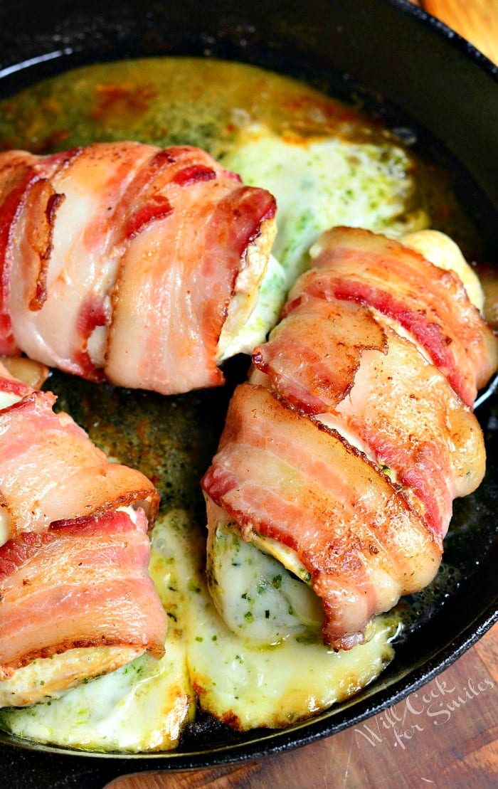 top view bacon wrapped chicken breast with cheese in a cast iron pan 