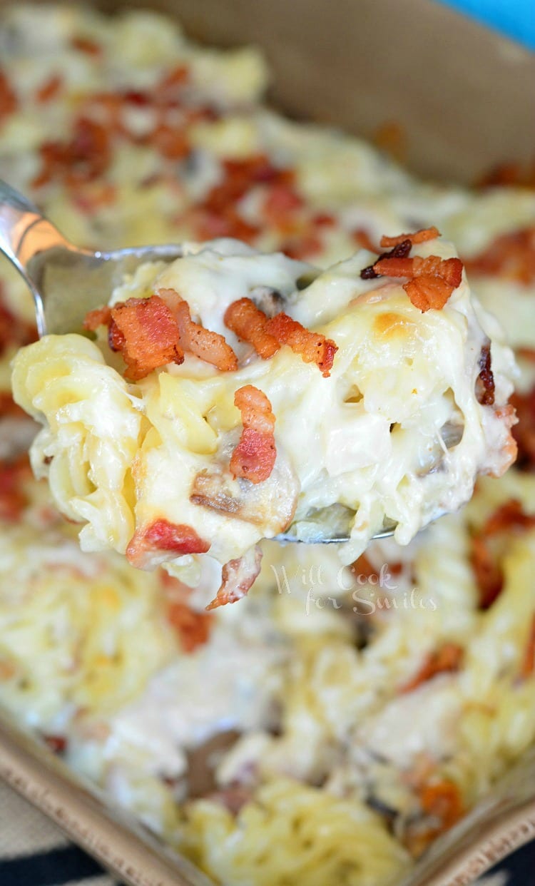 Chicken Bacon Alfredo Pasta Casserole being lifted out of baking dish with a spoon 