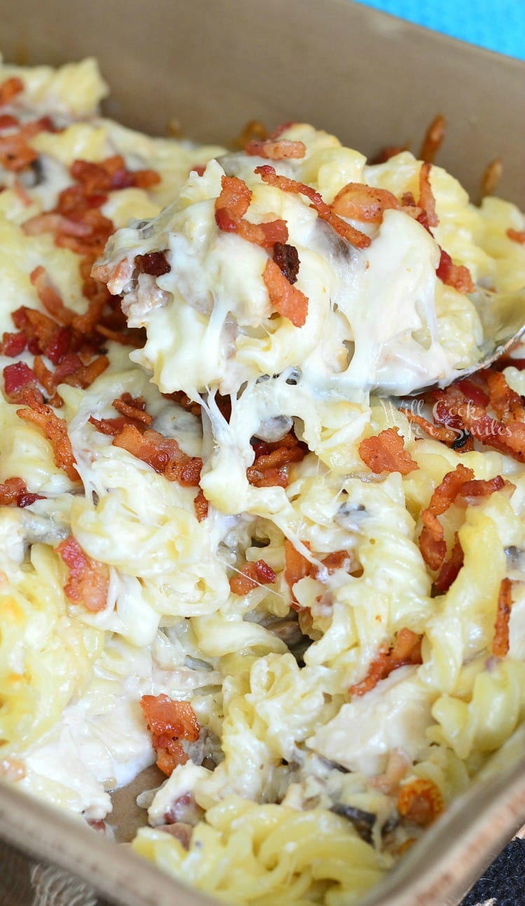  Chicken Alfredo Casserole in a casserole dish with a spoon scooping some out 