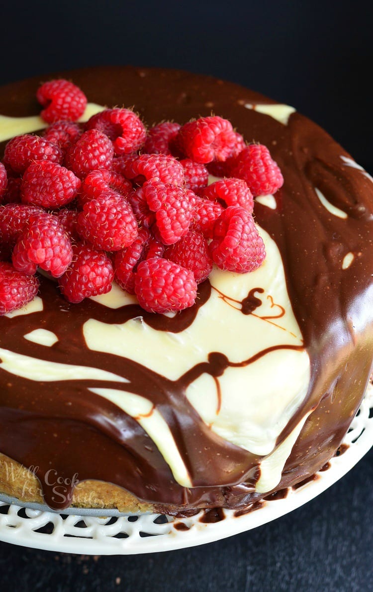 Top view of chocolate Ganache and Raspberry Cheesecake with raspberries on top on a cake stand 