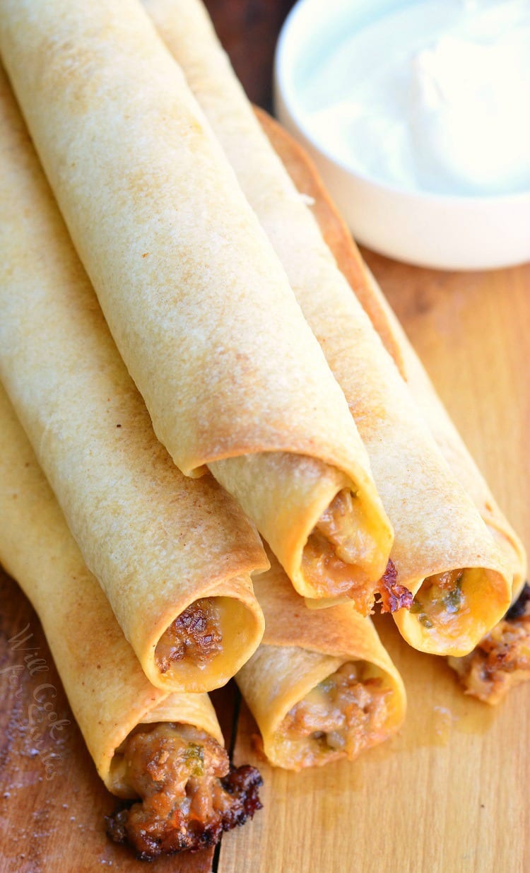 top view photo of Jalapeño Sausage and Cheese Taquitos stacked on a cutting board 