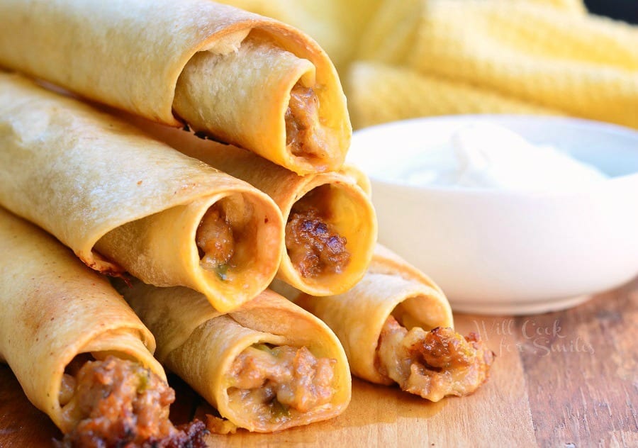 Jalapeño Sausage and Cheese Taquitos stacked on a cutting board 