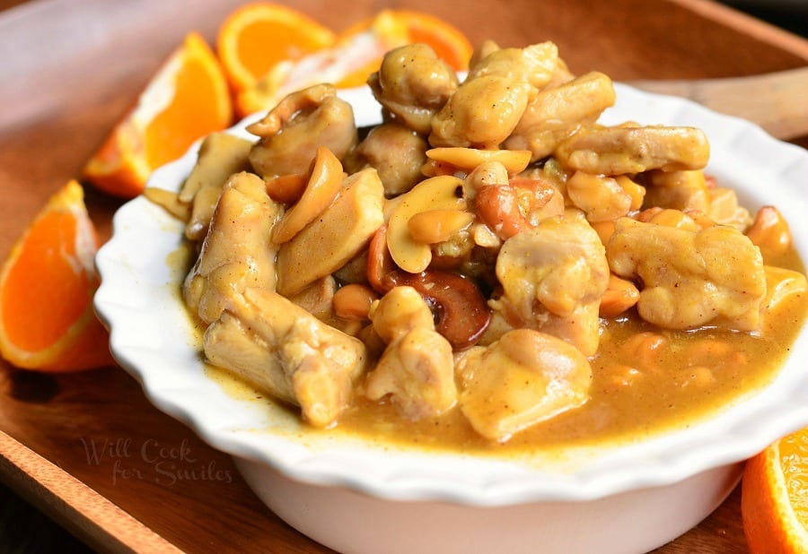 Nutty Light Orange Chicken in a white bowl with oranges around it 