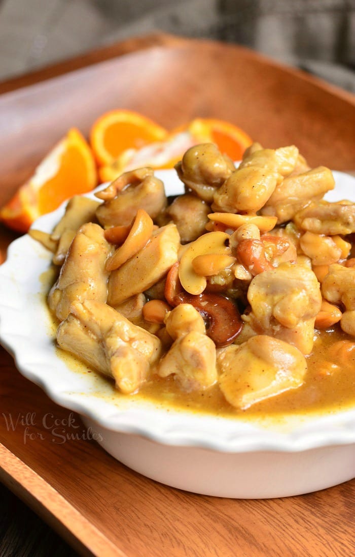 Nutty Light Orange Chicken in a white bowl with oranges around it 