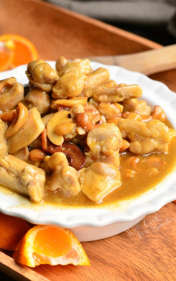 Nutty Light Orange Chicken in a white bowl on wood table 