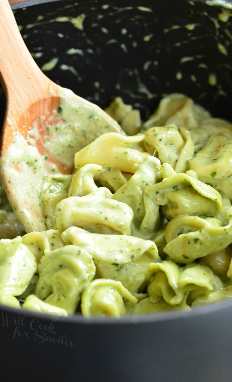 Pesto Alfredo Tortellini in a pot with a wooden spoon 