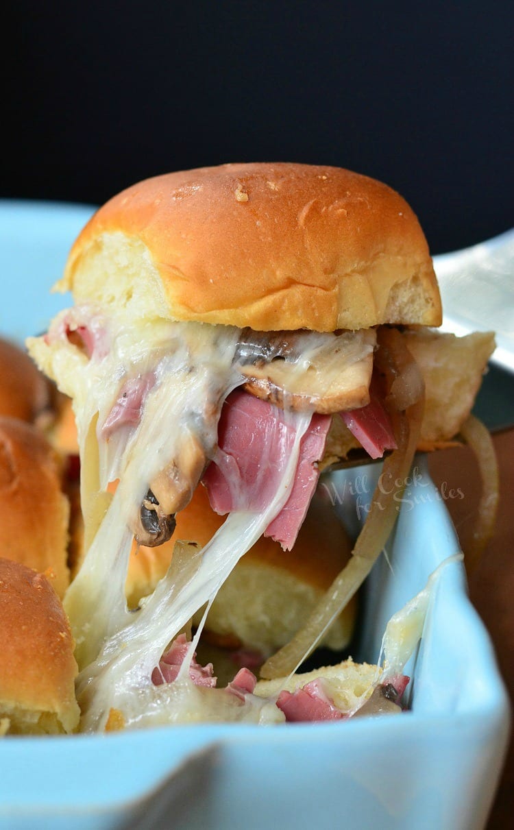 Baked Corned Beef Sliders on a spatula being lift out of a baking dish 