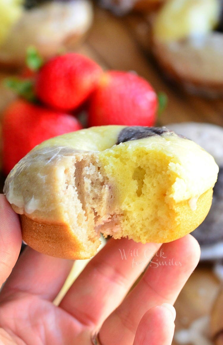 holding a Neapolitan Glazed Doughnut with a bite out of it 