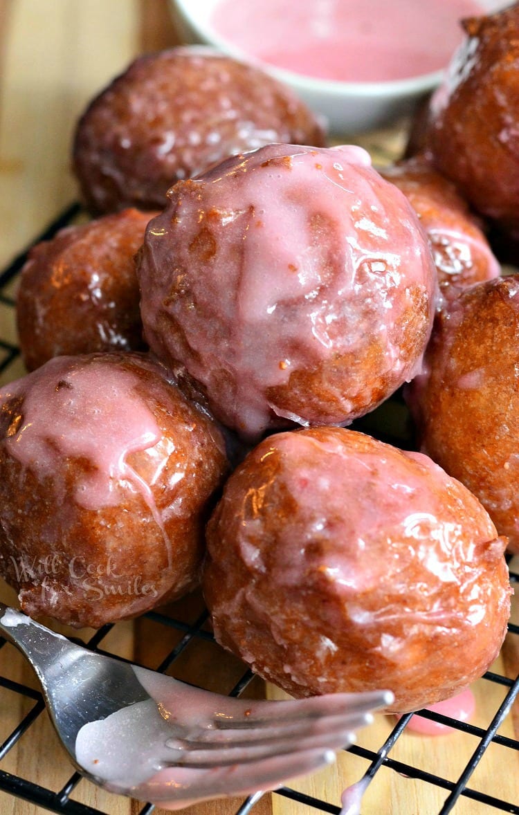 Glazed Strawberry Ricotta Doughnuts on a cooling rack with a fork in front of it 