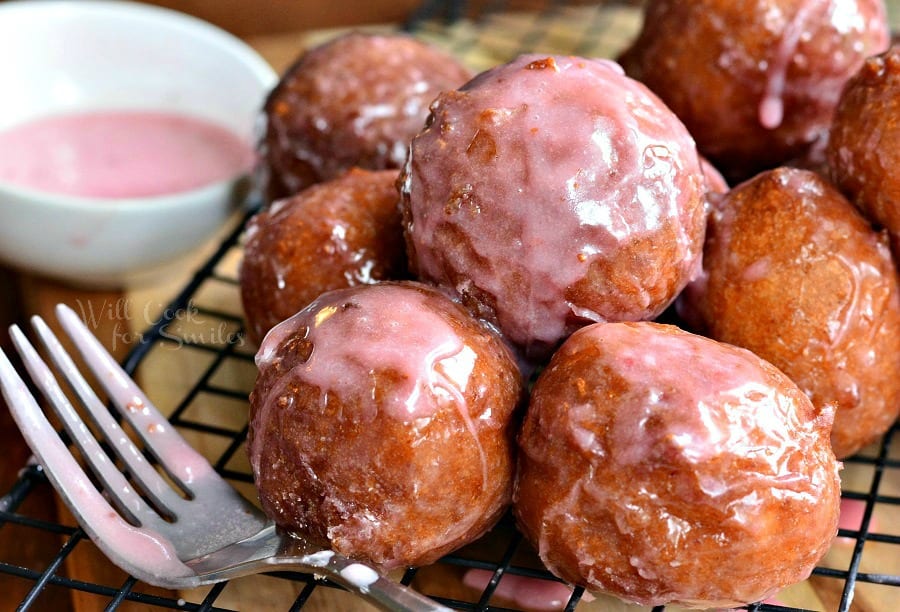 Glazed Strawberry Ricotta Doughnuts on a cooling rack with a fork to the side 