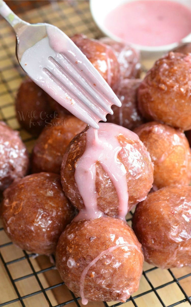 putting strawberry Glaze on Ricotta Doughnuts with a fork 