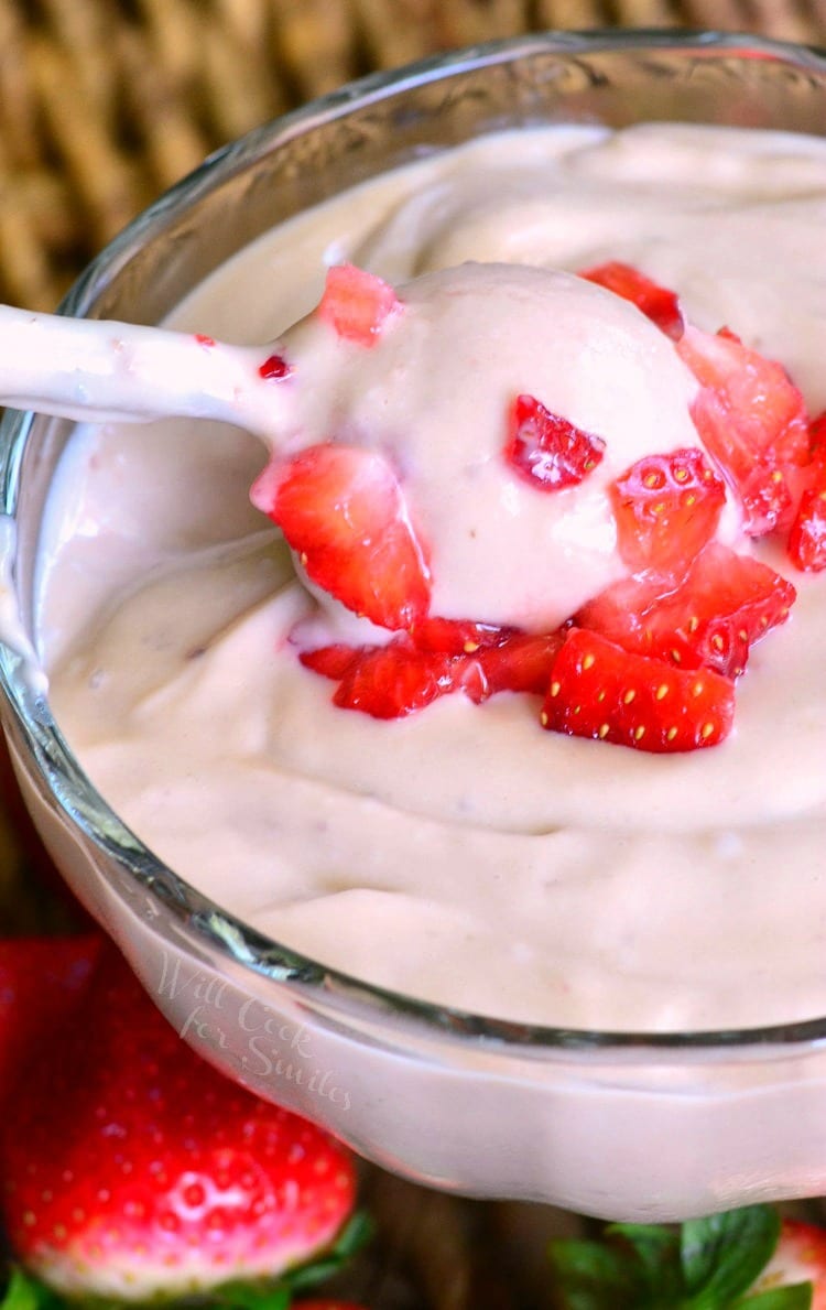 Strawberry Pudding in a bowl with strawberries on top and spoon getting some out 