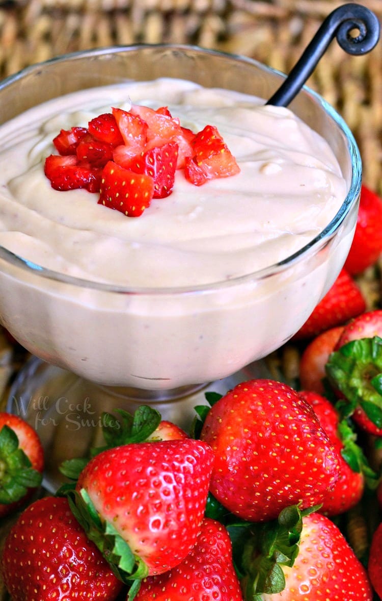 Strawberry Pudding in a glass bowl with cut strawberries on top and strawberries around the bottom of the bowl 