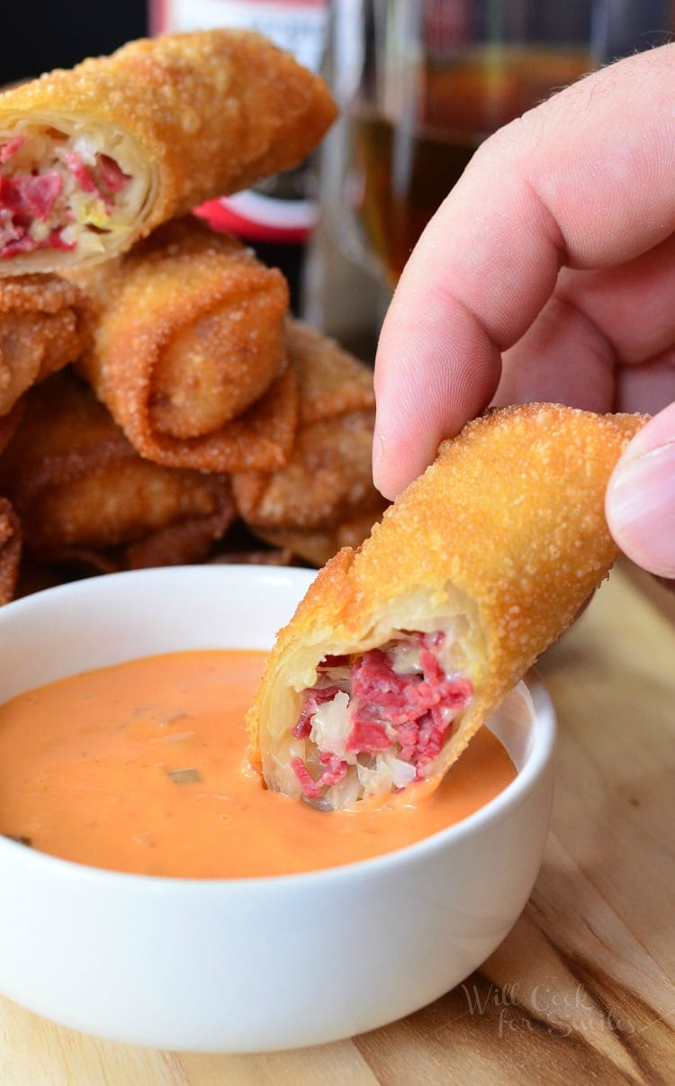 Reuben Egg Rolls dipping into a bowl 