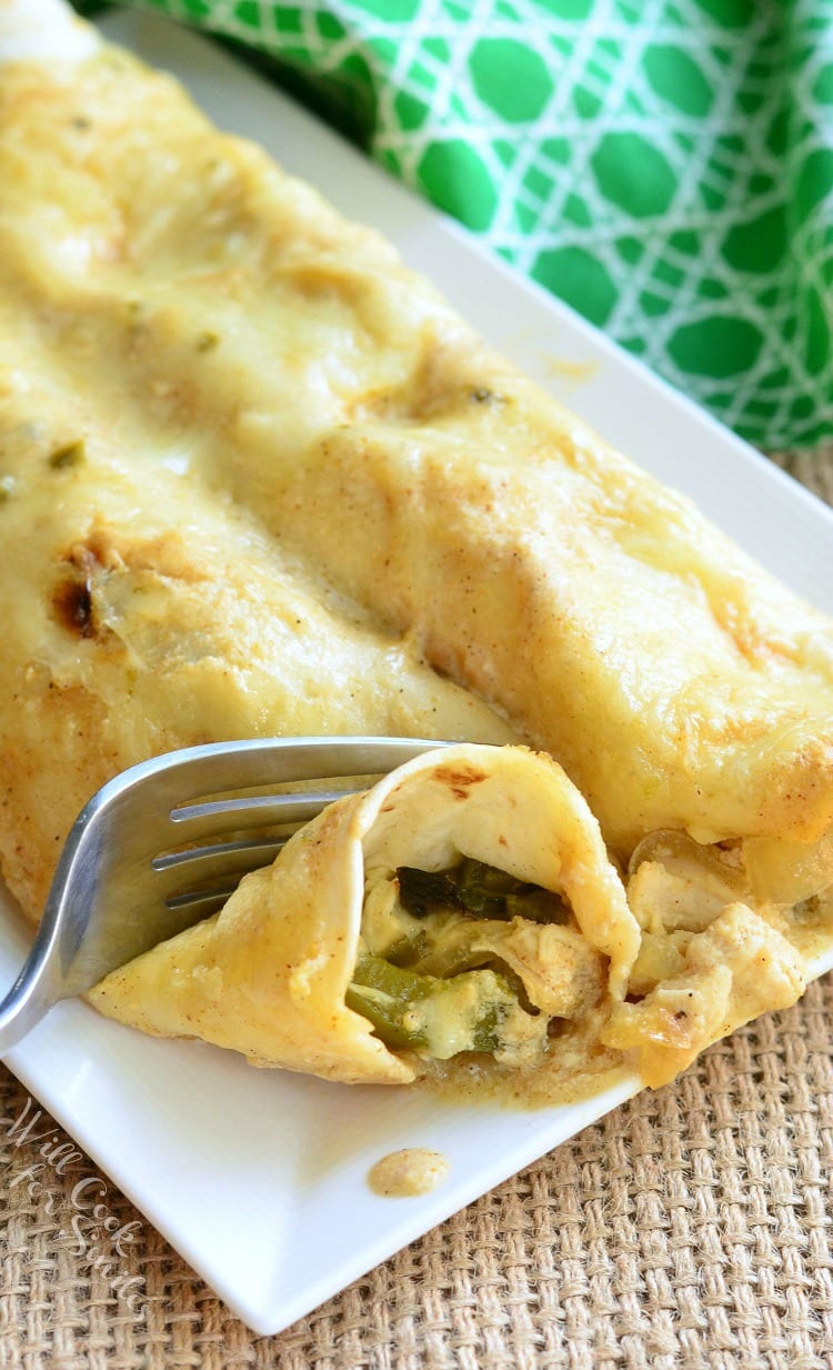 Roasted Poblano and Chicken Enchiladas on a white plate with a fork cutting some 