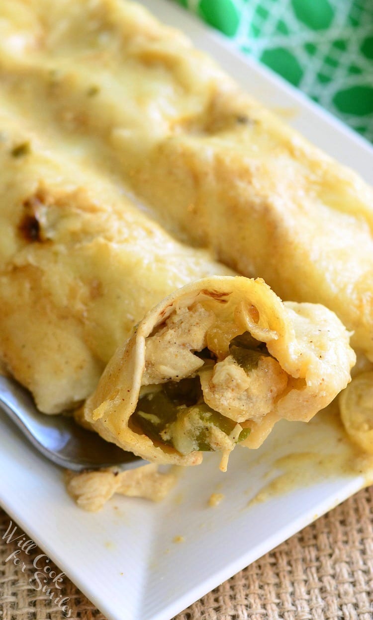 Roasted Poblano and Chicken Enchiladas on a plate with some of the enchiladas in a spoon 