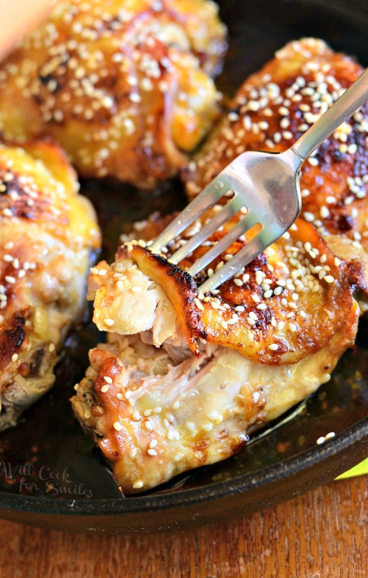 Sesame Roasted Chicken Thighs in a cast iron skillet with a fork pulling a piece off 