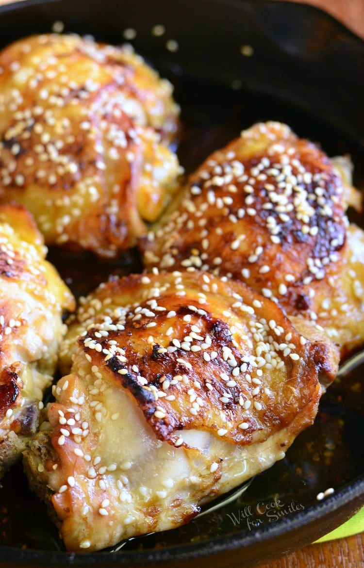 close up of cooked chicken thighs in a skillet with sesame seeds on top