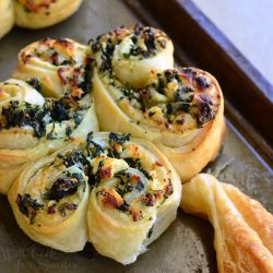 spinach and feta pastry shamrocks on a baking sheet pan as viewed close up