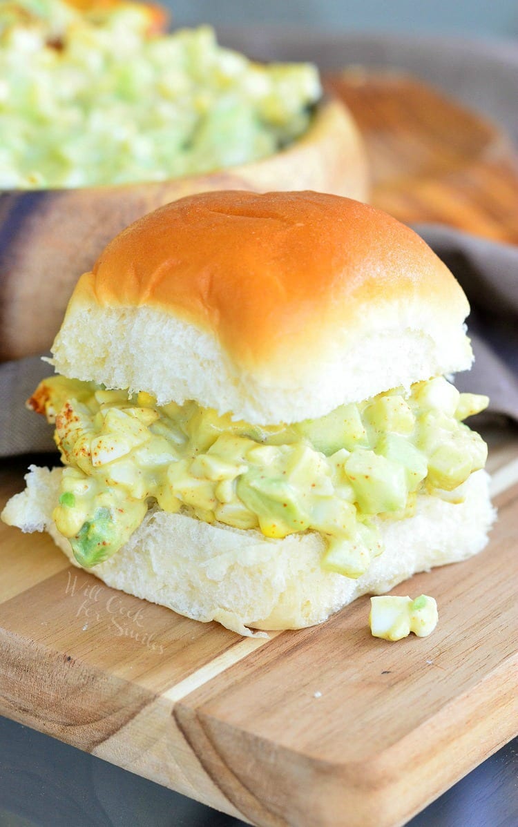 Avocado Cucumber Egg Salad in a bun on a wood cutting board 