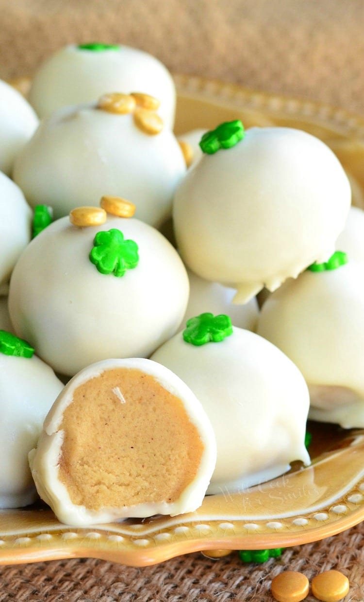Bailey's Cookie Dough Truffles with shamrock candy on top on a yellow plate with one cut in half 