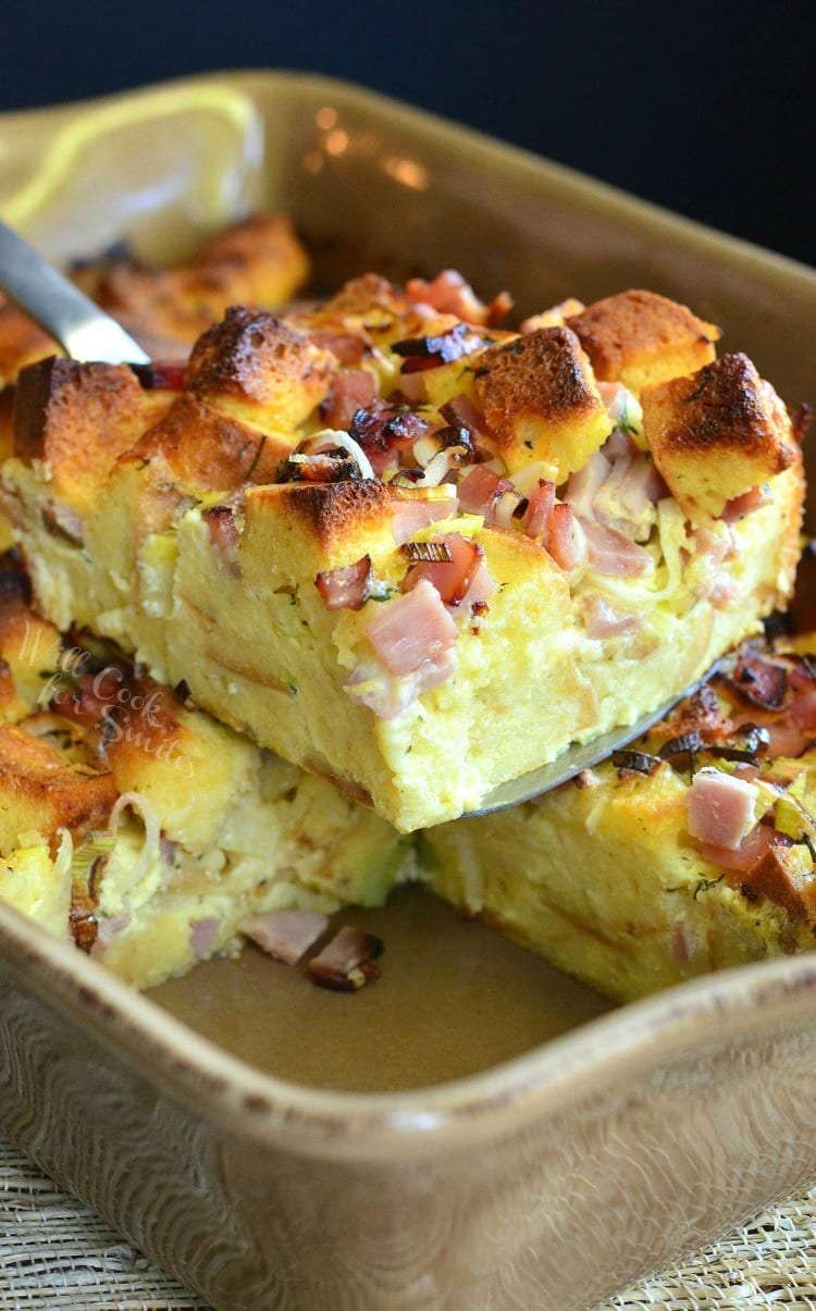 Ham Leek and Cheese Bread Pudding being lifted out of a baking pan with a spatula 