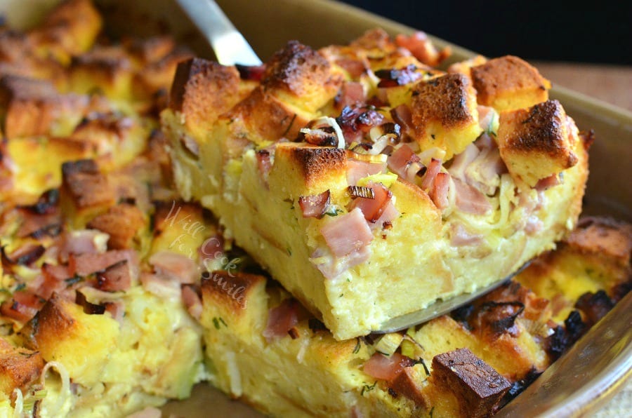 Ham Leek and Cheese Bread Pudding being lifted out of a baking pan with a spatula 